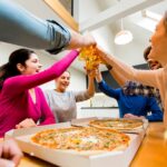 Groupe de jeunes heureux qui mangent de la pizza et de la consommation de cidre à l'intérieur moderne